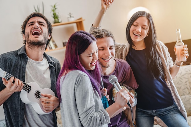 Junges süßes Mädchen, das Mikrofon hält und mit ihren Freunden Karaoke singt