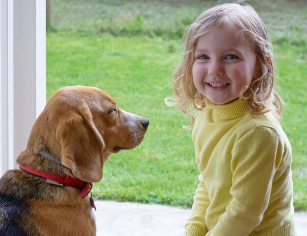 Junges süßes Mädchen mit Beagle-Hund, der im Garten spielt