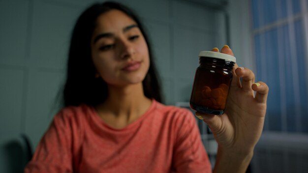 Junges Teenager-Mädchen hält Flasche mit Pillen und Medikamenten und liest ärztliche Verschreibung, um Medikamente einzunehmen