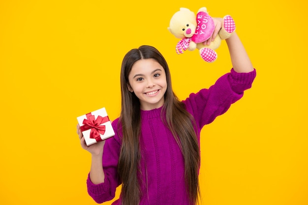 Junges Teenager-Mädchen mit Geschenkbox isoliert auf gelbem Hintergrund Geschenk für Kindergeburtstag