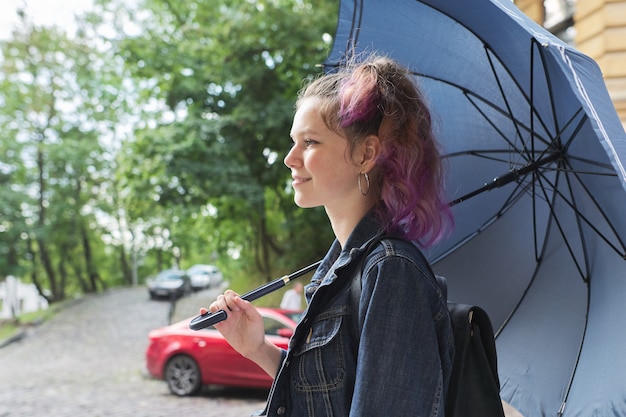 Junges Teenager-Mädchen unter einem Regenschirm auf der Straße der alten Stadt