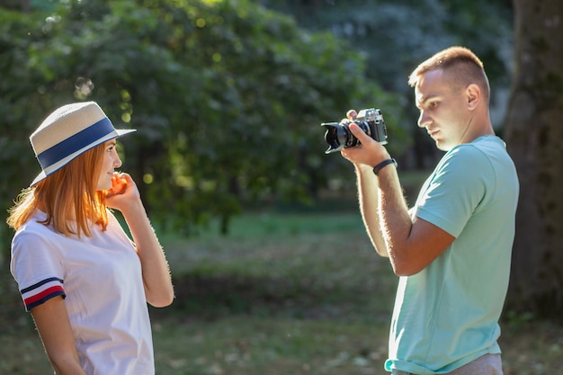 Junges Teenagerpaar, das draußen im sonnigen Sommerpark Fotos von einander macht