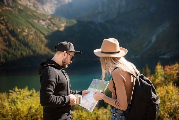 Junges Touristenpaar, Mann und Frau, auf Wanderweg in den Bergen, Karte halten und an sonnigen Tagen in der Natur zurechtfinden