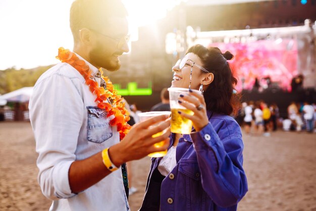 Junges und fröhliches Paar beim Musikfestival Fröhliche Freunde, die Bier trinken und Spaß haben