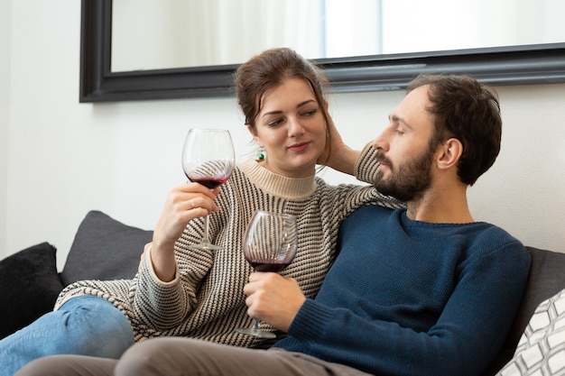 Junges und glückliches Paar, das Wein trinkt und sich zu Hause entspannt