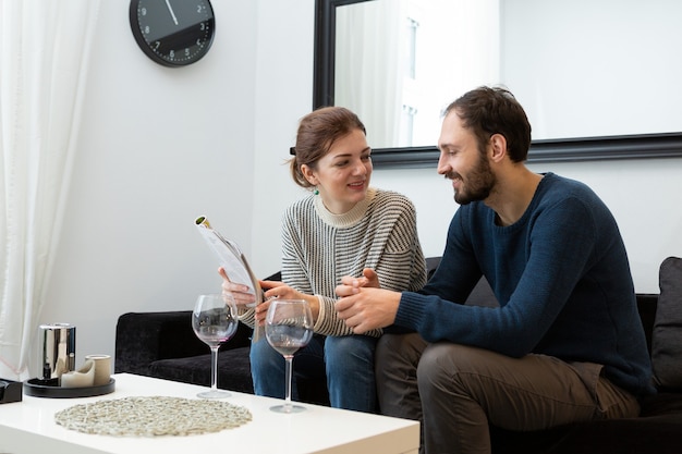 Junges und glückliches Paar, das Wein trinkt und sich zu Hause entspannt