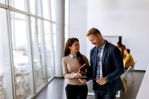 Junges Unternehmerpaar, das zusammen geht und digitales Tablet im modernen Büro verwendet