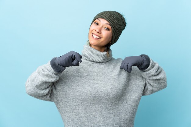 Junges uruguayisches Mädchen mit Wintermütze lokalisiert auf blau stolz und selbstzufrieden