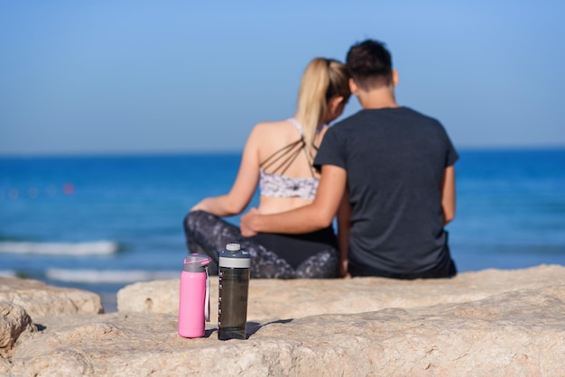 Junges verliebtes Paar sitzt am felsigen Strand und blickt auf den Horizont auf dem Meer