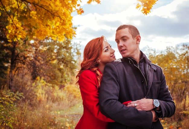 Junges verliebtes Paar umarmt sich im Herbstwald zwischen bunten Bäumen. Romantisches Date