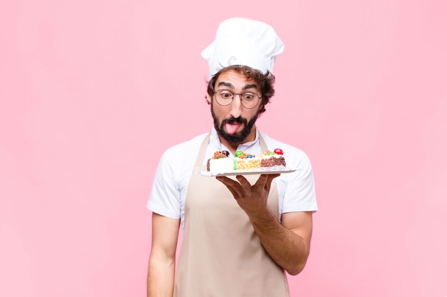 Junges verrücktes Bäcker-Mann-Süßwarenkonzept gegen rosa Wand