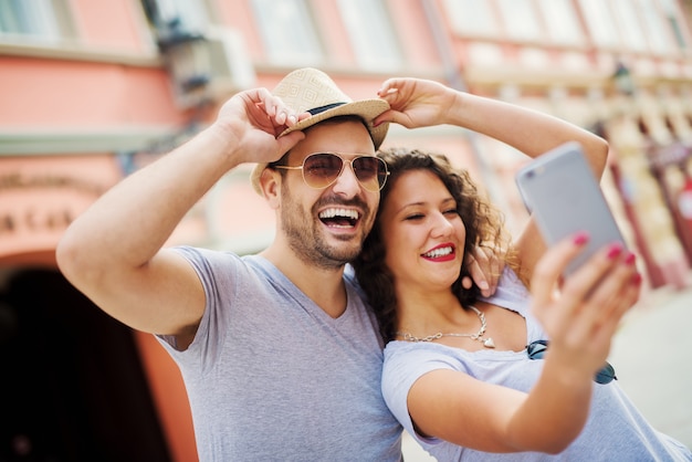 Junges verspieltes Paar mit Sonnenbrille, die ein Selfie nimmt.