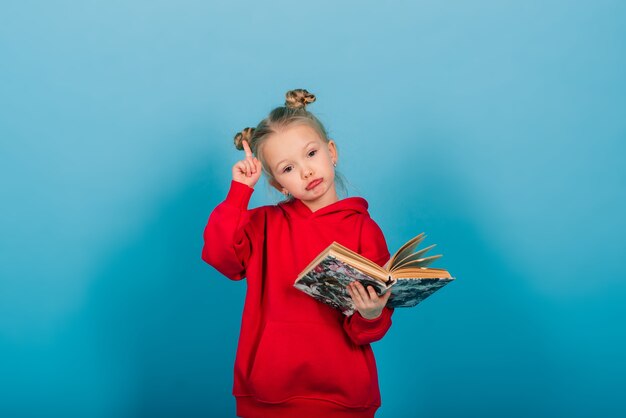 Junges Vorschulkind lernt beim Lesen eines Buches, isoliert auf Blau