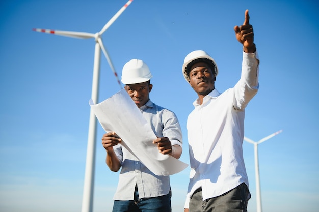 Junges Wartungstechnikerteam, das bei Sonnenuntergang im Windturbinenpark arbeitet stockfoto