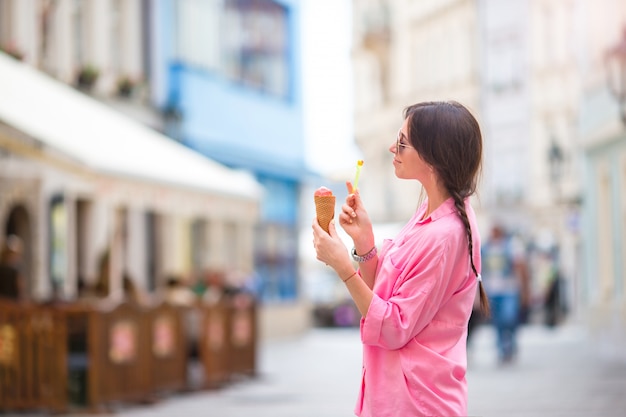 Junges weibliches Modell, das draußen Eistüte isst. Sommerkonzept - Frau mit süßer Eiscreme am heißen Tag