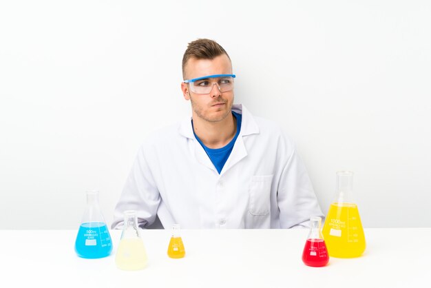 Junges wissenschaftliches mit Lots Laborflasche stehend und zur Seite schauend