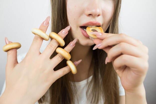 Foto junges wunderschönes mädchen isst bagels in nahaufnahme von pflanzenfoto attraktive brünette sexy frau isst einen köstlichen donut