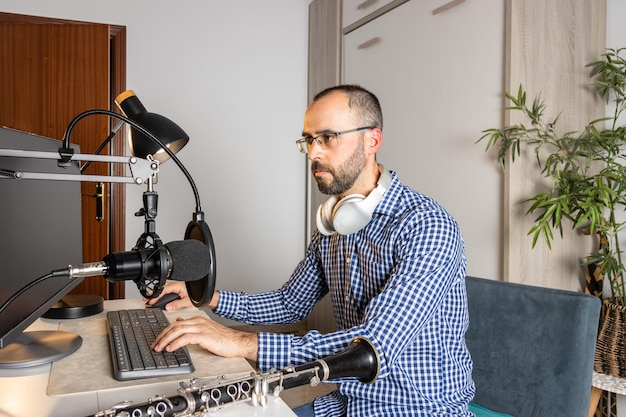 Jungunternehmer spielt zu Hause Klarinette und nimmt Musik auf, um sie mit seinem Computer online zu streamen