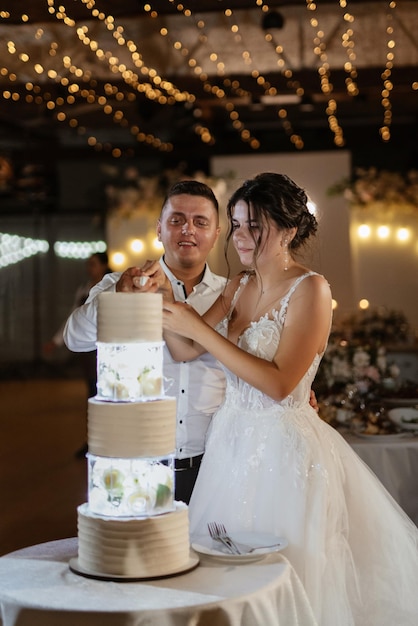 Jungvermählte schneiden und schmecken glücklich den Hochzeitskuchen