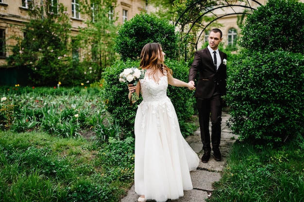 Jungvermählten auf dem richtigen Weg im Garten. Romantischer Hochzeitsmoment.