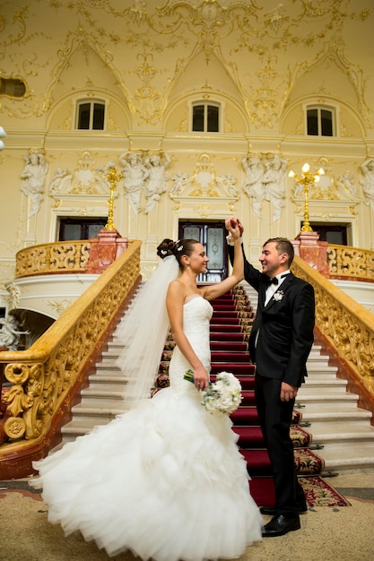 Jungvermählten halten ihre Hände im Palast hoch.
