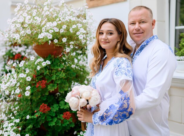 Jungvermählten in nationalen Hochzeitsoutfits umarmen