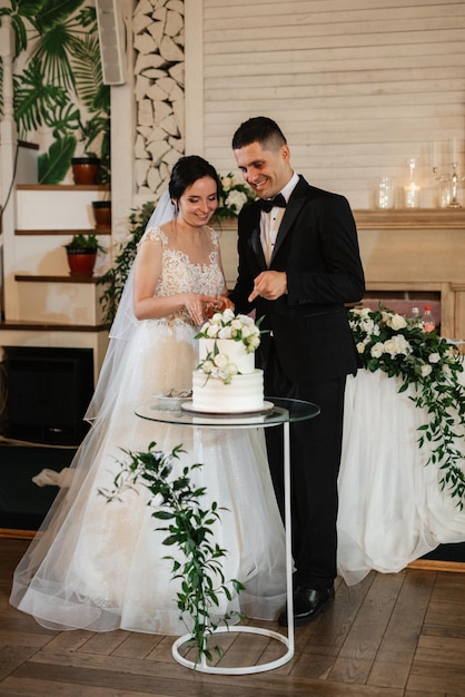 Jungvermählten schneiden glücklich lachen und probieren die Hochzeitstorte