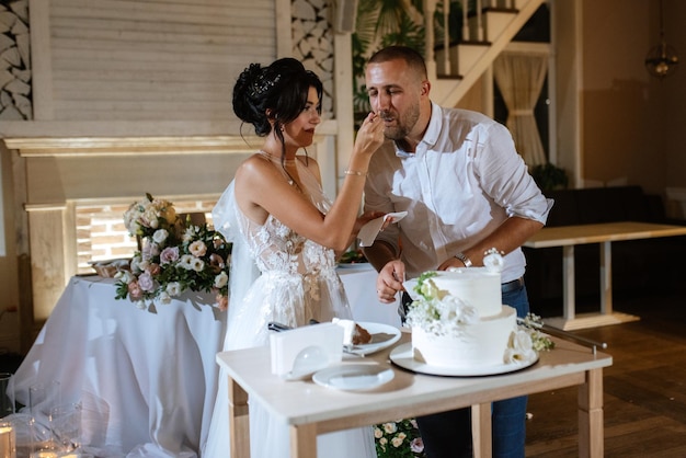 Jungvermählten schneiden glücklich lachen und probieren die Hochzeitstorte