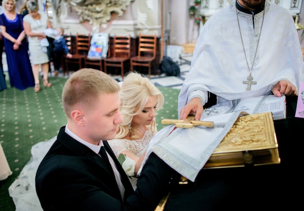 Jungvermählten stehen auf den Knien vor dem Priester