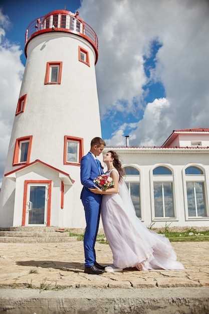 Jungvermählten umarmen und küssen nahe Leuchtturm an der Hochzeit