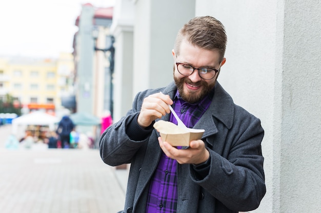 Junk Food, Essen und Lifestyle-Konzept - junger Mann mit Mahlzeit isst auf der Stadtstraße.