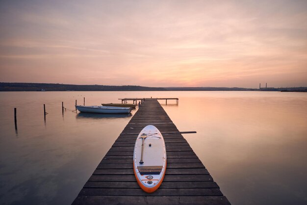 Junta de SUP en un embarcadero en el lago al atardecer en Varna Bulgaria