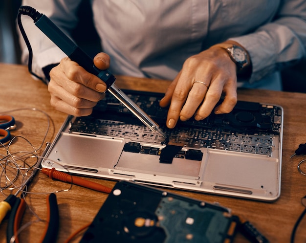 Juntando as peças novamente Foto recortada de uma técnica de informática feminina irreconhecível consertando um laptop em sua oficina