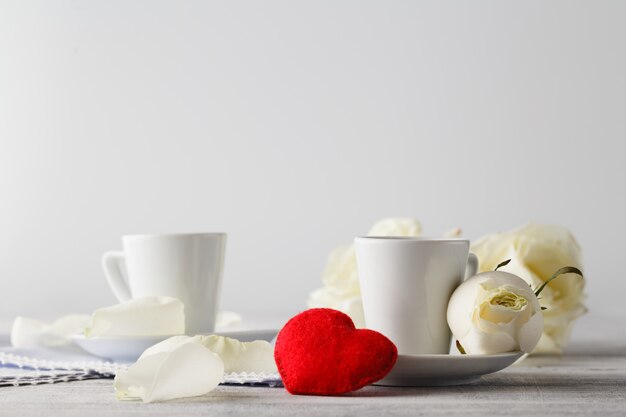 Junte las tazas blancas con la decoración de los corazones rojos en la tabla de madera. Concepto de celebración del día de san valentín