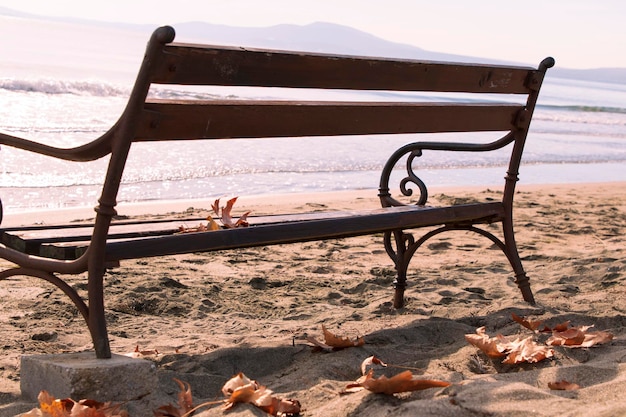 Junto al mar, banco en la playa en otoño