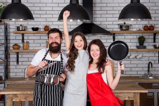 Juntos é mais saboroso mãe pai e filha aventais na cozinha conceito de culinária preparar um delicioso café da manhã hora do almoço família se divertindo cozinhando juntos ensinar criança a cozinhar comida cozinhar juntos