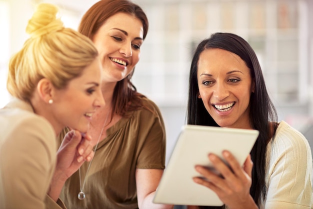 Juntos, nunca les faltan grandes ideas Foto de tres compañeros de trabajo usando una tableta digital juntos en una oficina