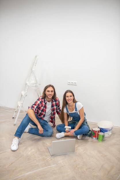 Juntos. Pareja joven sentada en el suelo y sonriendo