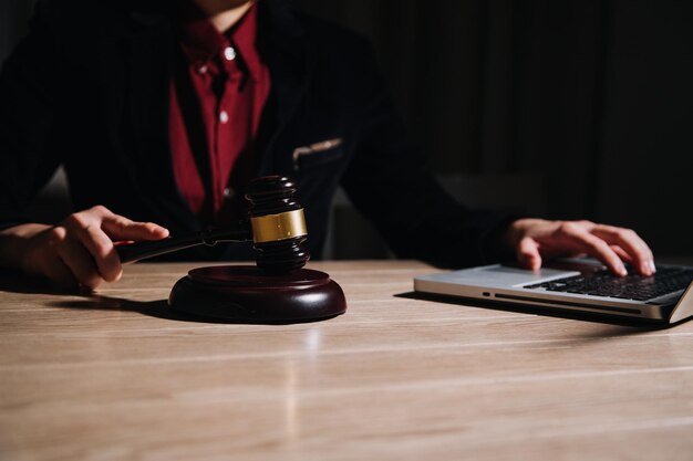 Justiz- und RechtskonzeptMännlicher Richter in einem Gerichtssaal mit dem Hammer, der mit dem Computer arbeitet und im Morgenlicht eine Tastaturbrille auf dem Tisch andockt