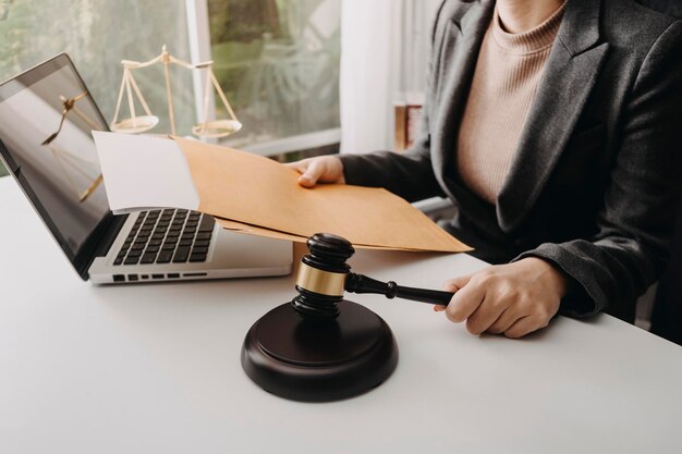 Justiz- und RechtskonzeptMännlicher Richter in einem Gerichtssaal mit dem Hammer, der mit dem Computer arbeitet und im Morgenlicht eine Tastaturbrille auf dem Tisch andockt