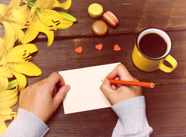 Foto justo por encima de la fotografía de una mujer escribiendo en papel junto al café en la mesa