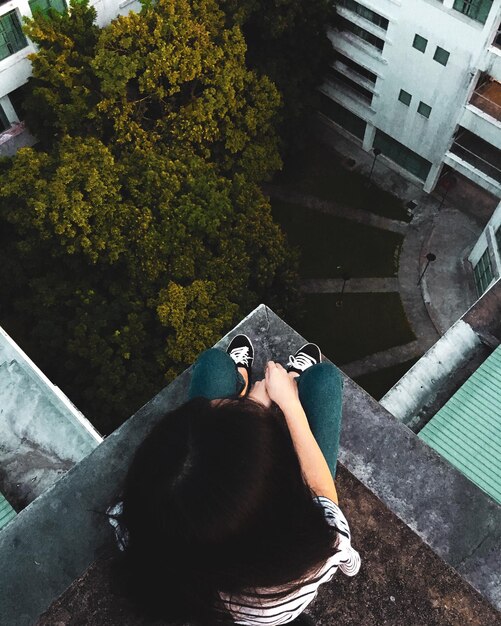 Foto justo por encima de la fotografía de una mujer sentada en la terraza de un edificio en la ciudad