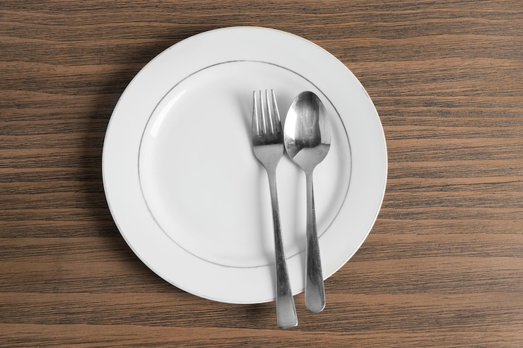 Foto justo por encima de la toma de un plato vacío con tenedor y cuchara en una mesa de madera