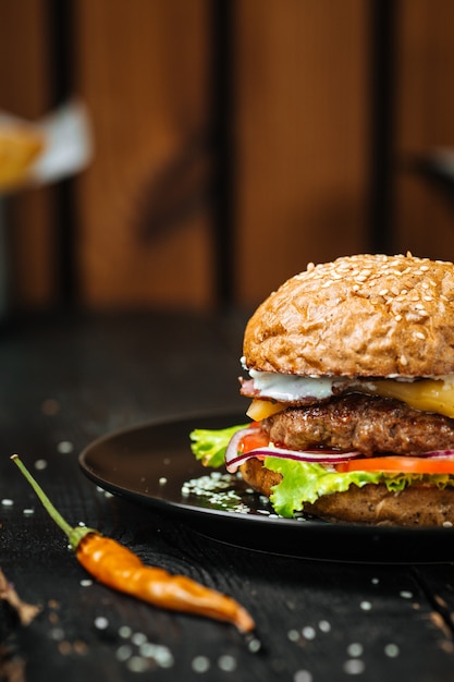 Jusy Cheeseburger auf einem dunklen Holztisch