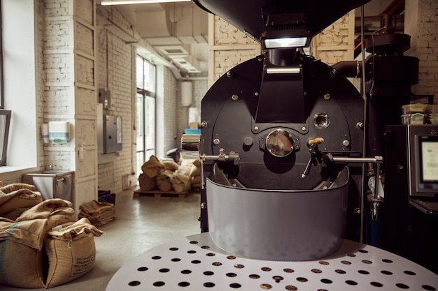 Jutesäcke mit Kaffeebohnen und professionelles Equipment zum Rösten in der Fabrik
