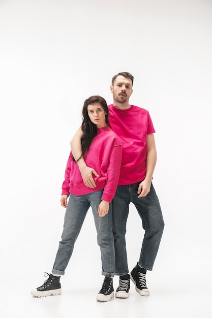 Juventud. Pareja de moda de moda aislada sobre fondo blanco de estudio. Mujer caucásica y hombre posando en ropa elegante gris rosa básica. Concepto de relaciones, moda, belleza, amor. Copyspace.