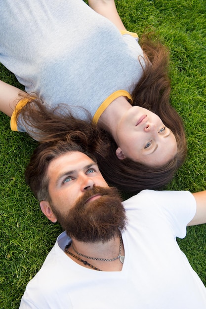 Juventude e liberdade. Casal apaixonado relaxante leigos. Frescura e paz. Hipster barbudo homem e menina feliz despreocupada apreciam a vista superior da natureza da primavera. Relaxe na grama da primavera. Fique à vontade. Tempo de primavera.