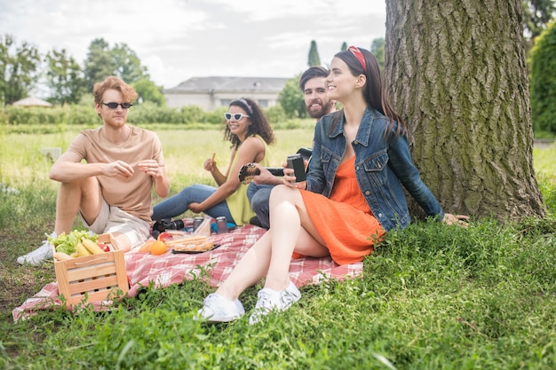 Juventude, piquenique. Jovens felizes e fofos se socializando e passando momentos de lazer com comida de violão na natureza em dia de verão