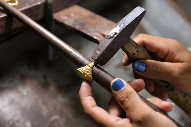 Foto juwelier, der mit dem hammer auf goldring in seiner werkstatt arbeitet