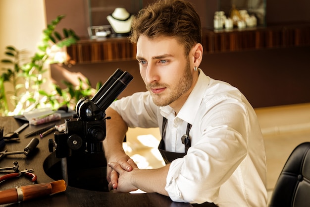 Juwelier sitzt an einem Tisch in der Nähe eines Mikroskops